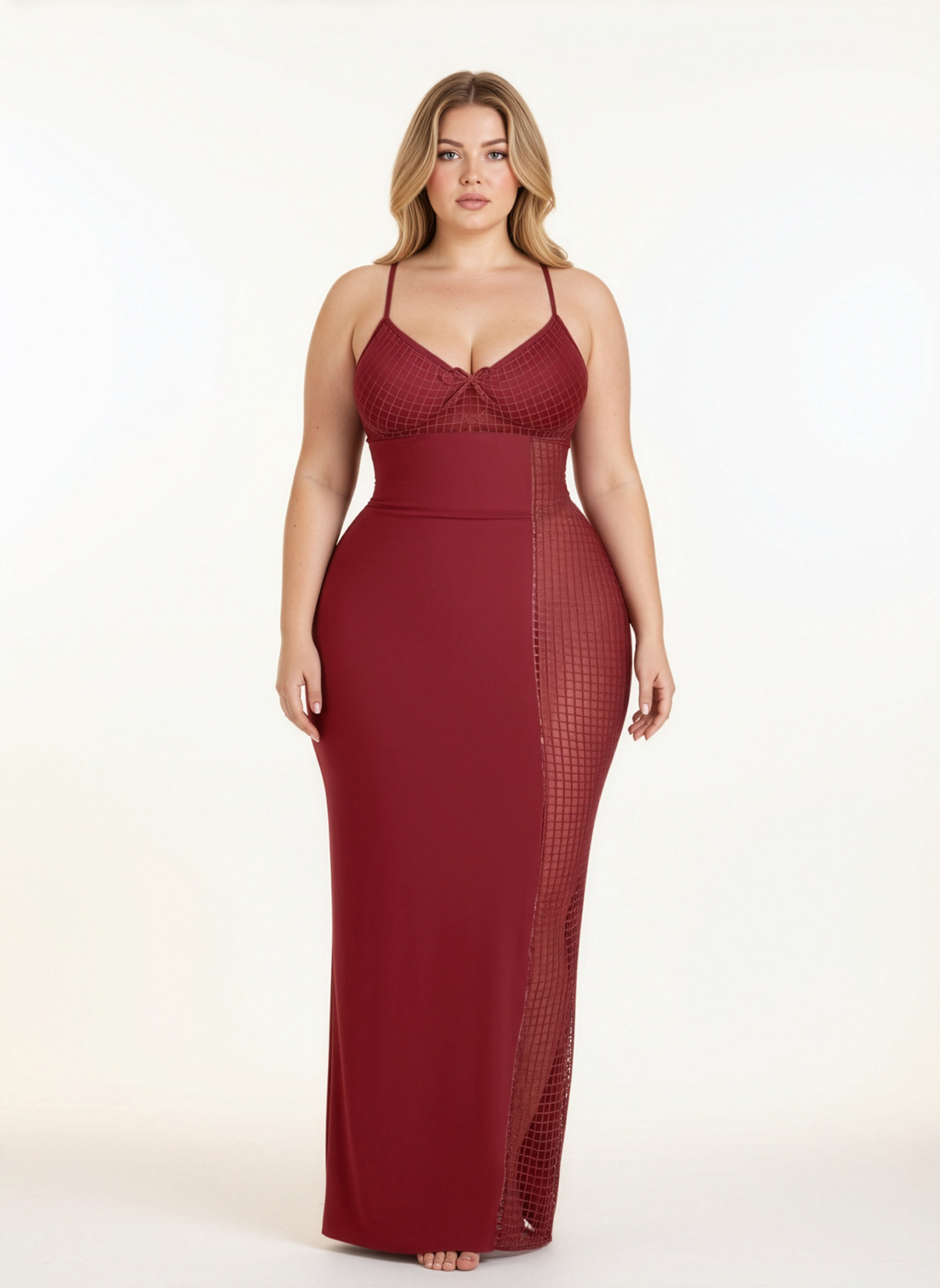 Woman wearing a burgundy evening gown with mesh panels on a white background